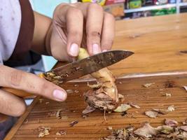 un' galangal essere tagliare con coltello foto