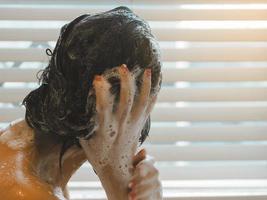 asiatico donna lavaggio sua capelli rilassare a partire dal opera foto