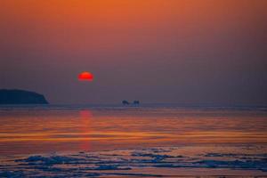 vista sul mare spiaggia di ghiaccio e il tramonto rosso. foto