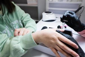 vicino su mano di manicure maestro Lavorando con femmina cliente nel bellezza salone. manicure fa donna chiodo. foto