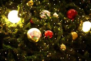 sfocato vicino su decorazione palla e leggero lampadina su Natale albero a notte foto