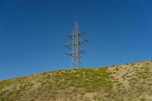 torre elettrica su una collina contro un cielo blu. foto