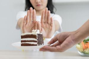 dieta, dieta malsano asiatico giovane donna mano nel spingere fuori, rifiutando mangiare cioccolato torta o dolce gusto, combattente per mantenere esso a partire dal ottenere Grasso quando persona portare per me. sano, nutrizione di peso perdita foto