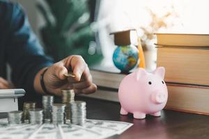 mano mettendo moneta su pila con porcellino banca. concetto di Salvataggio i soldi per un' Borsa di studio per studia all'estero a un' Università livello. finanziario pianificazione contabilità idee per futuro formazione scolastica. foto