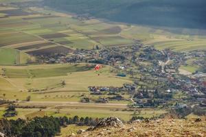 singolo colorato parapendio a un' montagna nel un' verde valle foto