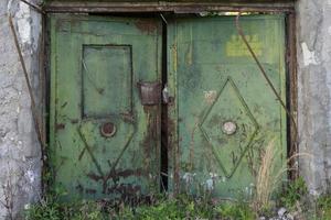 vecchio cancello di metallo sullo sfondo di un muro di mattoni grigi. foto