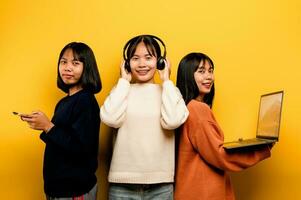 tre asiatico donne Lavorando con il computer portatile e Telefono a il stesso tempo il Due di loro erano comunicare in linea e mostrando contento sorrisi. e ascolta per musica in giro e amici concetto in linea comunicazione foto