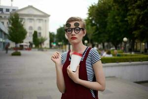 donna su il strada parlando su il Telefono indossare bicchieri bicchiere con bevanda moda foto