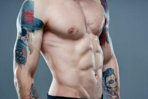 sexy atleta con nudo torso e pompato su muscoli tatuaggio grigio sfondo modello foto