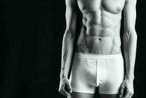 maschio atleta nel bianca pantaloncini gonfiato corpo bodybuilder il buio sfondo foto