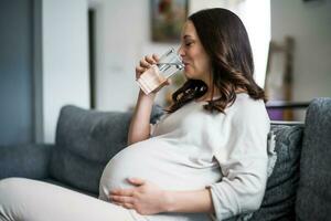 incinta donna potabile acqua a casa. foto