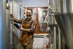 uomo è Lavorando a mestiere birra fabbrica. lui è operativo macchinari nel birrificio. piccolo famiglia attività commerciale, produzione di mestiere birra. foto