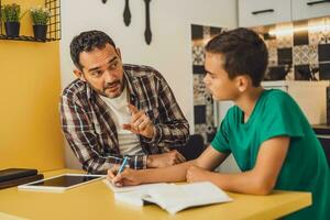 padre è porzione il suo figlio con apprendimento. essi siamo fare compiti a casa insieme. foto