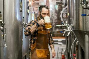 uomo è Lavorando a mestiere birra fabbrica. lui è operativo macchinari nel birrificio. piccolo famiglia attività commerciale, produzione di mestiere birra. foto