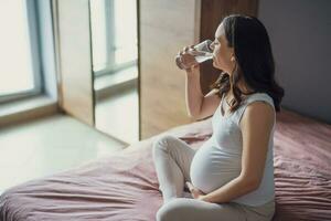 incinta donna potabile acqua a casa. foto