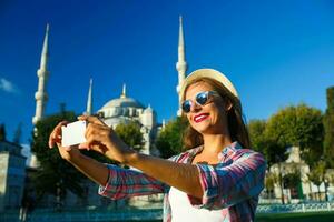 ragazza fabbricazione autoscatto di il smartphone su il sfondo di il blu moschea, Istanbul. tacchino foto