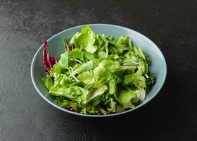 verde insalata le foglie nel ciotola su nero tavolo. foto