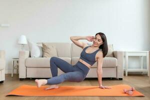asiatico donna esercizio a casa, allungamento. tempo per yoga. attraente e salutare giovane donna fare esercizi mentre riposo a casa. giovane donna esercizio a casa, interno foto
