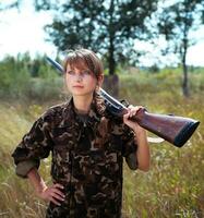 giovane bellissimo ragazza con un' fucile da caccia sembra in il distanza foto