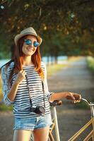 bello giovane donna nel un' cappello equitazione un' bicicletta nel un' parco foto