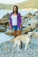 donna con un' cane su un' camminare su il spiaggia foto