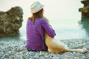 donna con un' cane seduta su il spiaggia foto