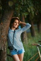 bello giovane donna nel un' cappello con un' bicicletta nel un' parco foto