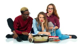 tre contento studenti con libri, il computer portatile e borse isolato su bianca foto