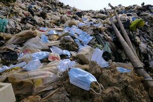 maschere mediche usate scartate lungo la spazzatura, spazzatura con altri detriti di plastica giace a terra