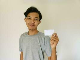 contento divertente viso asiatico uomo mostrare via il suo vuoto carta su bianca sfondo foto
