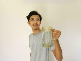 asiatico uomo è potabile un' bicchiere di acqua e contento foto