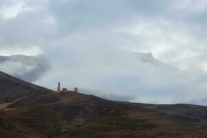 nebbioso mattina nel il Caucaso montagne. medievale Torre su nebbioso foto