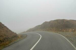 girare su un' montagna strada nel il nebbia. autostrada attraverso il passaggio nel di spessore nebbia. foto