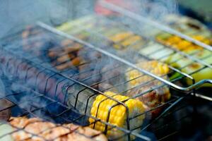 avvicinamento grigliato verdure su il griglia. Mais, fungo e Pepe avvicinamento siamo cucinato su un' barbecue, Fumo a partire dal un' fuoco. foto