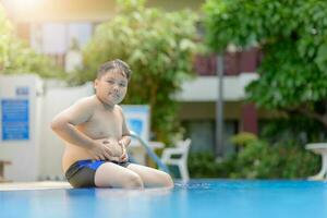 obeso Grasso ragazzo sedersi su nuoto piscina foto