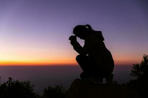 silhouette con copia spazio di donne mano preghiere o culto su superiore di montagna e Alba cielo astratto sfondo. Eucaristia terapia Dio benedice aiuto, speranza, e fede, cristiano religione concetto. foto