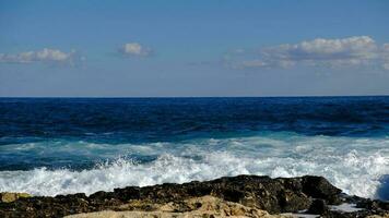 blu mare onda e bianca schiuma e spruzzata. pietra spiaggia su isola di Malta, no sabbioso spiaggia. estate vacanza confine telaio concetto. tropicale isola vacanza sfondo. turista viaggio bandiera design modello. foto