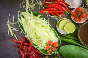 tailandese cibo superiore Visualizza - papaia insalata speziato con erbe aromatiche e spezie condimenti e ingredienti con chili pomodoro Limone lime papaia fetta, tailandese cibo concetto foto