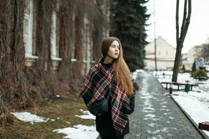 giovane bellissimo ragazza con sciarpa e inverno cappotto passeggiate su un' nevoso giorno foto