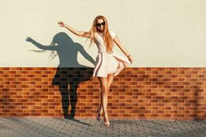 bellissimo giovane allegro ragazza con un' Sorridi salto vicino il parete. avere divertimento foto