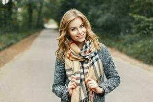 contento giovane ragazza nel un' cappotto e Vintage ▾ sciarpa nel autunno parco foto