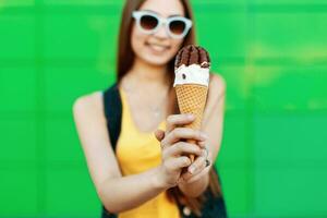 bellissimo allegro ragazza sorridente e Tenere un ghiaccio crema. delizioso ghiaccio crema cono avvicinamento. foto