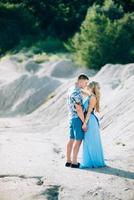 ragazza bionda in un vestito azzurro e un ragazzo con una camicia leggera in una cava di granito foto