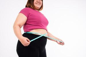 un sovrappeso donna le misure sua pancia Grasso su un' bianca sfondo. concetto di sano, cibo per Salute e stile di vita foto