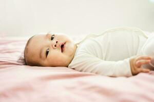 Immagine di un' neonato bambino dire bugie su un' rosa letto foto
