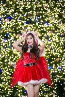 bella asiatico ragazza nel Santa costume per Natale con notte leggero foto
