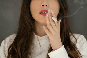 giovane asiatico donna fumo su il strada, selettivo messa a fuoco foto