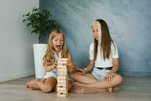 sorella ragazze siamo giocando un' tavola gioco di posa di legno blocchi dopo scuola. divertimento parti per bambini, vacanze a casa foto