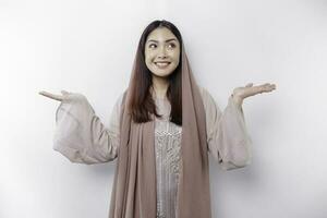 giovane asiatico musulmano donna sorridente mentre puntamento per copia spazio accanto sua foto