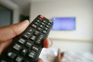 primo piano della mano dell'uomo che tiene il telecomando della tv. foto